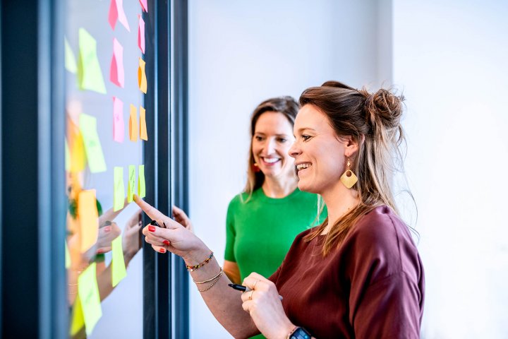"Sticky marketing owners Meike & Lotte aan het sparren naast de sticky's m.b.t marketing" Dit beeld staat naast de 3 kernwaarden van Sticky Marketing: Hands-on, Energie en Spot-on